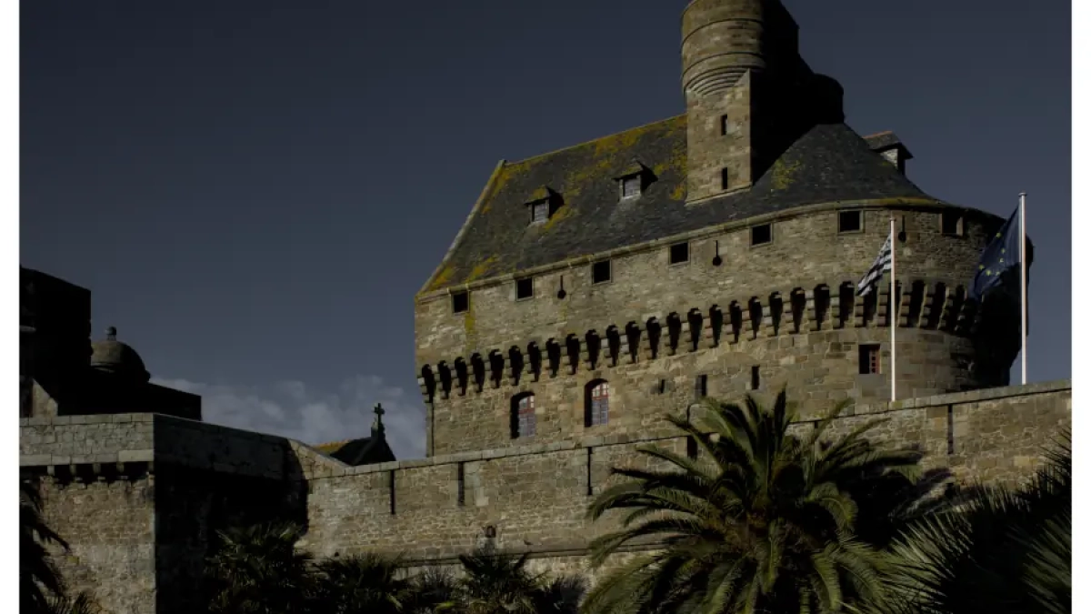 A fine art print of a medieval French castle displayed in a dark, atmospheric living room interior