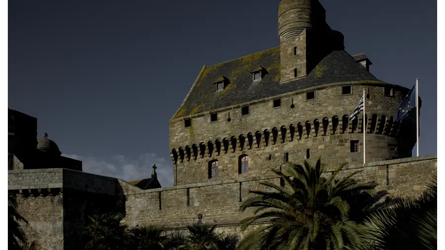 A fine art print of a medieval French castle displayed in a dark, atmospheric living room interior