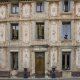 Historic ochre facade with floral frescoes and a carved wooden door in Fontaine-de-Vaucluse.